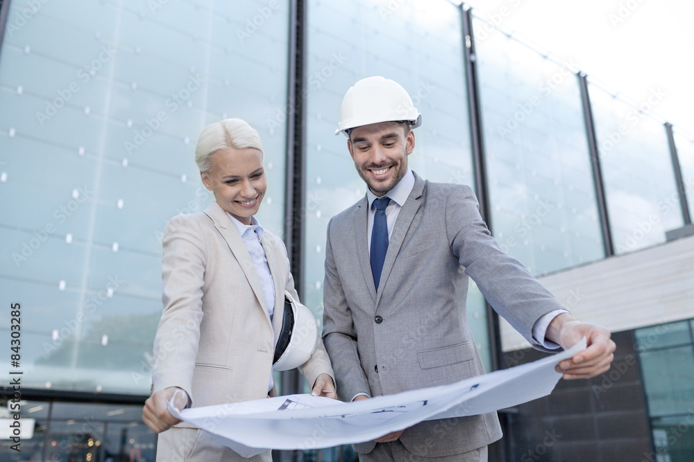 smiling businessmen with blueprint and helmets smiling businessmen with blueprint and helmets