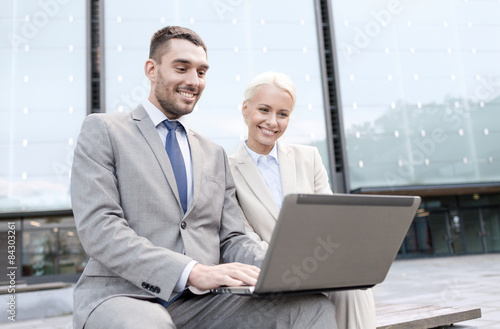 smiling businesspeople with laptop outdoors © Syda Productions