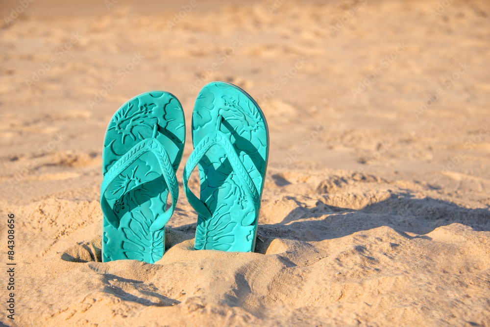Fototapeta premium Flip flops stuck in the sand of a beach