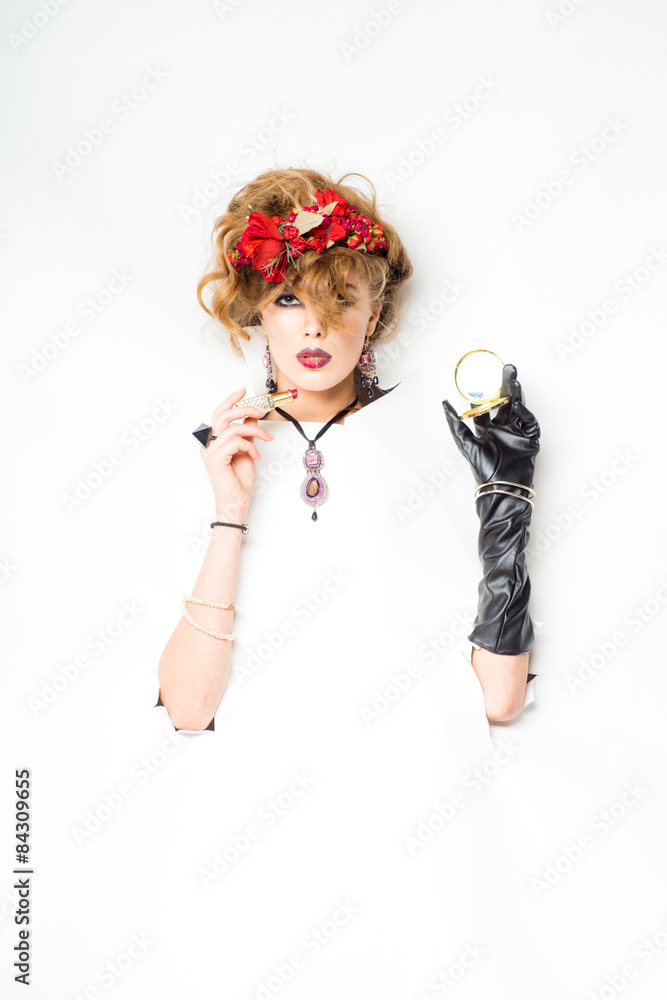 woman with red flowers in hair doing make-up woman with red flowers in hair doing make-up