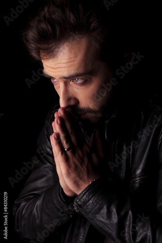 young man holding his hands together praying.
