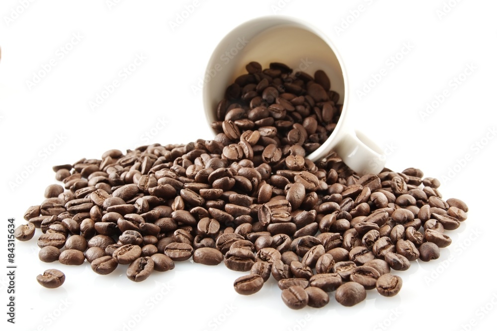 Overturned cup full of coffee beans on white Overturned cup full of coffee beans on white