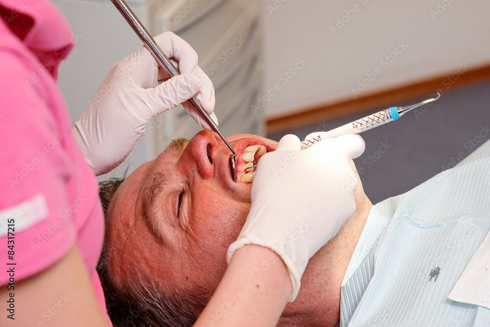 man is getting his teeth checked at the dentist's office man is getting his teeth checked at the dentist's office