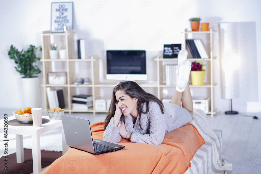 Woman in bed with coffee, tablet, computer, phone laughing Woman in bed with coffee, tablet, computer, phone laughing