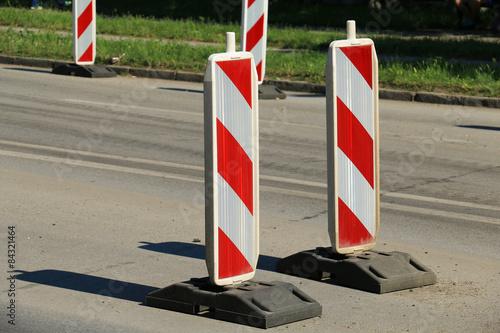 Road works marked with red and white striped road warning posts 