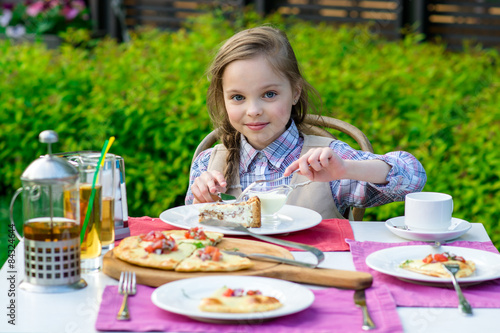 cute little girl sitting by dinner table and eating