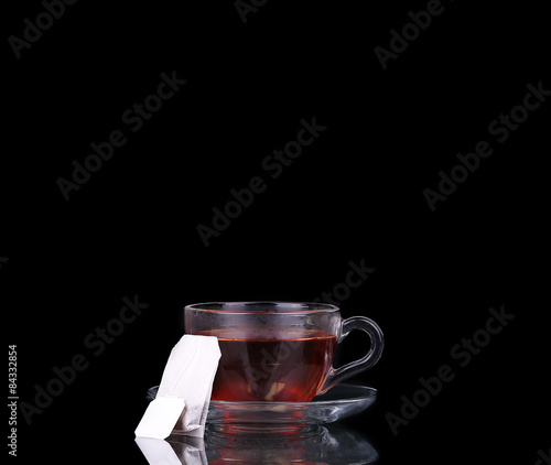 Glass cup on black. Tea bag. Boiling water.