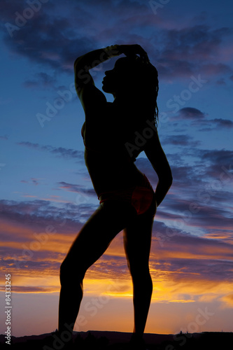 silhouette of a woman in a bikini side hand on head and hip