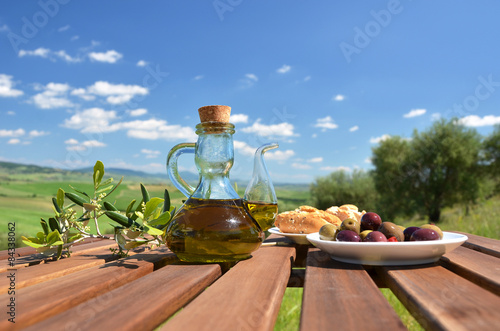 Olive oil, olives and bread on the wooden table against Tuscan l