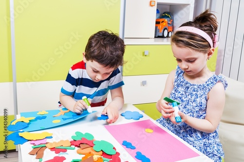 Two preschool child create a picture with foam shapes