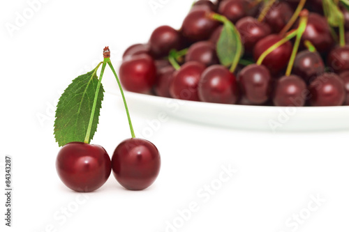 Two ripe berries with green leaf and plate of cherry (isolated)