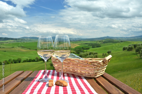 Two wineglasses and cantuccini on the wooden table Tuscan landsc photo