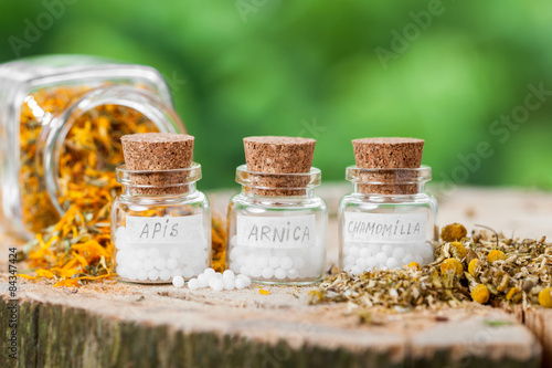 Three bottles of homeopathy globules and healthy herbs. photo