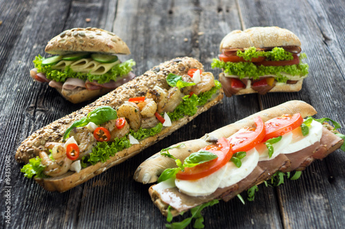 Mixed sandwiches with crispy baguette on a wooden background 