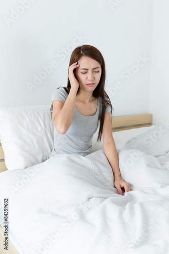 Woman got headache and sitting on bed