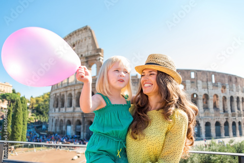 Photography Smiling mother and daughter with pink balloon by Colosseum
