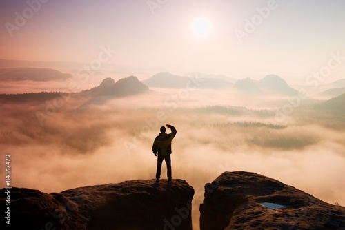Man stands on peak of sandstone rock in national park 