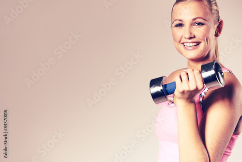 Woman smiling at camera and holding dumbbell.