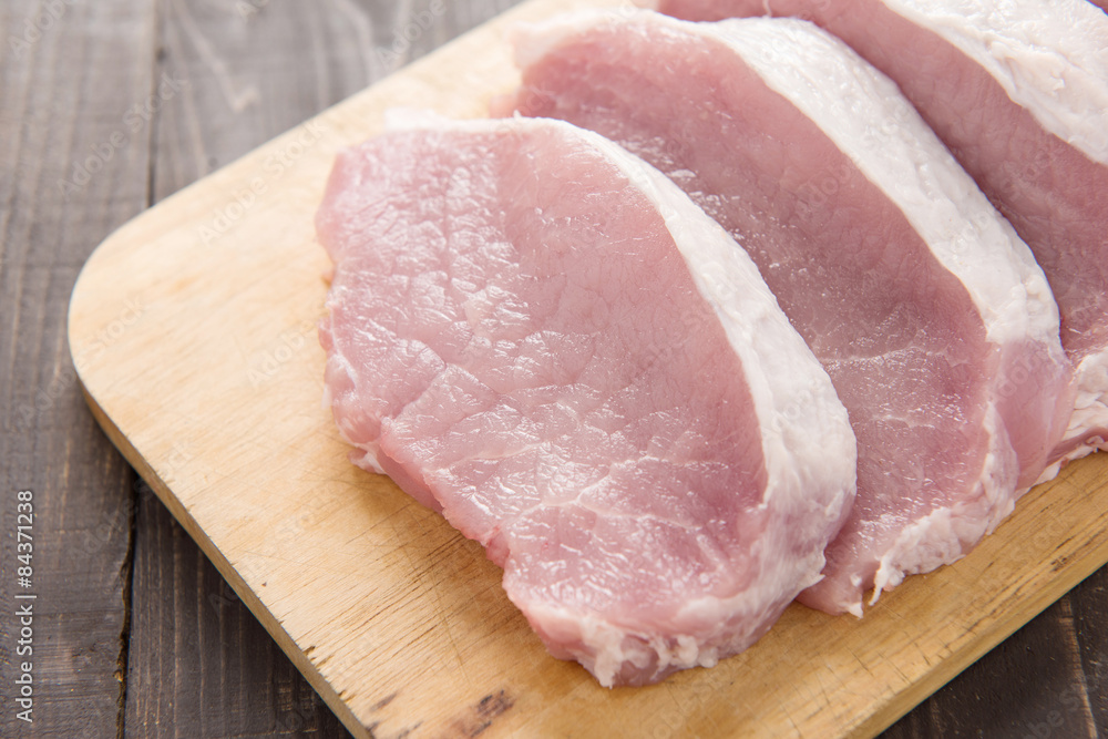Raw pork on cutting board on wooden background. Raw pork on cutting board on wooden background.