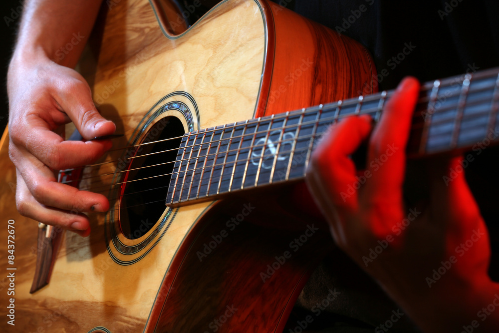Fototapeta premium Young man playing on acoustic guitar close up