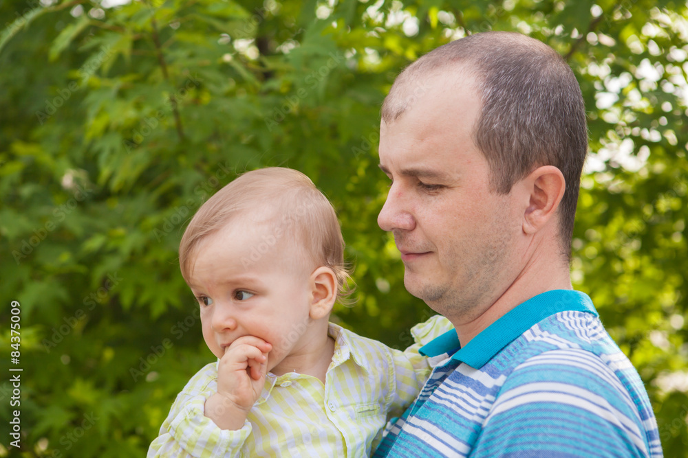 father holds a small child in his arms, outdoors in a park father holds a small child in his arms, outdoors in a park