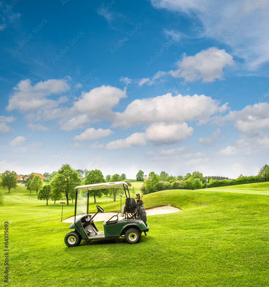 Golf cart on a golf course. Green field and cloudy blue sky