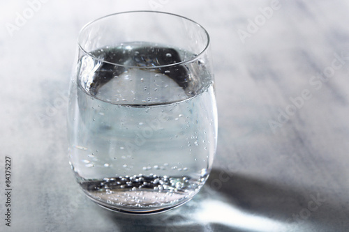 Glass of water with bubbles on table close up
