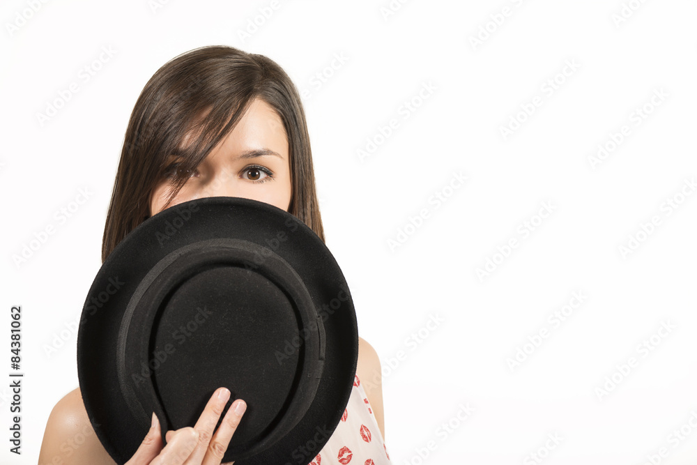 Happy expressive beautiful girl hiding her face behind a black hat Happy expressive beautiful girl hiding her face behind a black hat