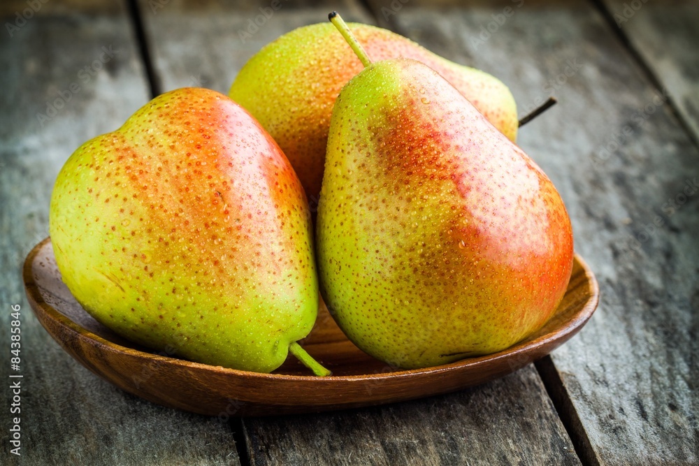 Three fresh ripe organic pears in a wooden bowl Three fresh ripe organic pears in a wooden bowl