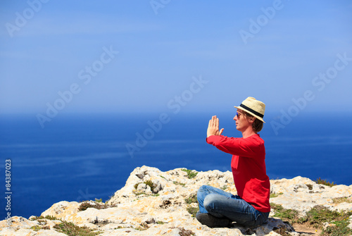 man doing yoga in summer mountains