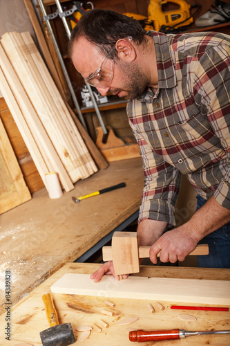 Carpenter hammering wood dowel in a piece of wood