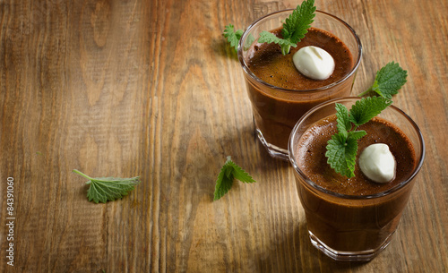 Homemade Chocolate Mousse in glasses on  rustic wooden table.