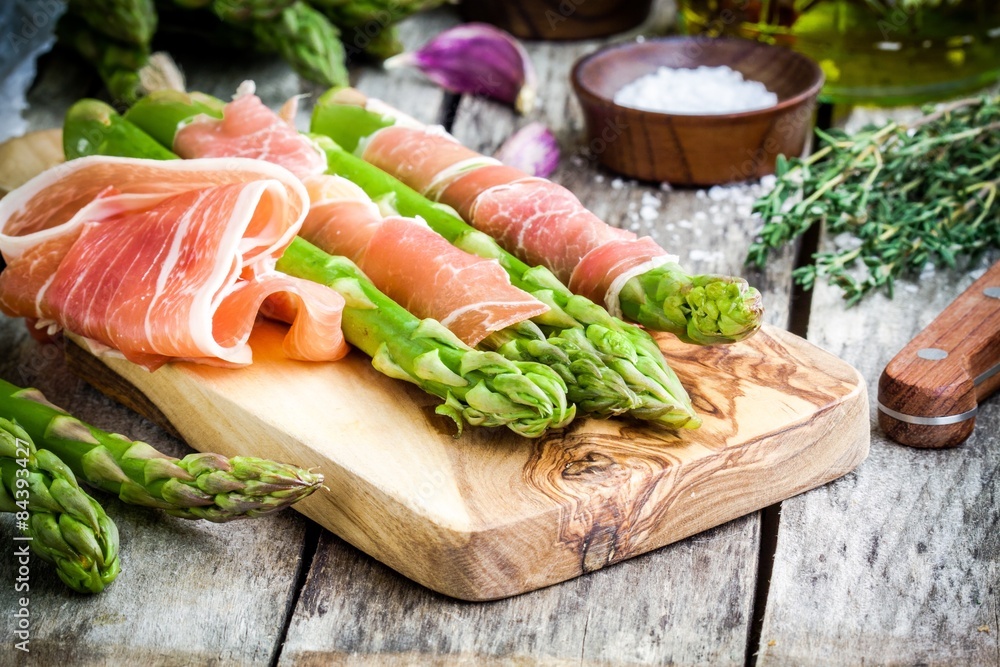 Fresh organic asparagus with prosciutto on a cutting board Fresh organic asparagus with prosciutto on a cutting board