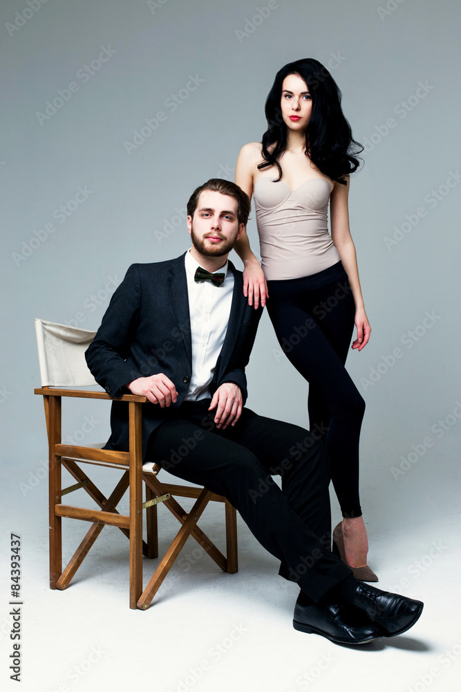 Fototapeta premium Handsome man in suit and pretty brunette female model on grey background
