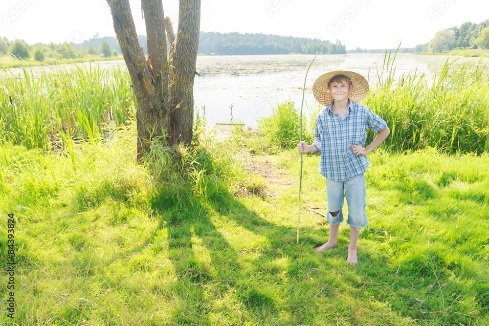 Smiling angling teenage boy with handmade green twig fishing rod in hand