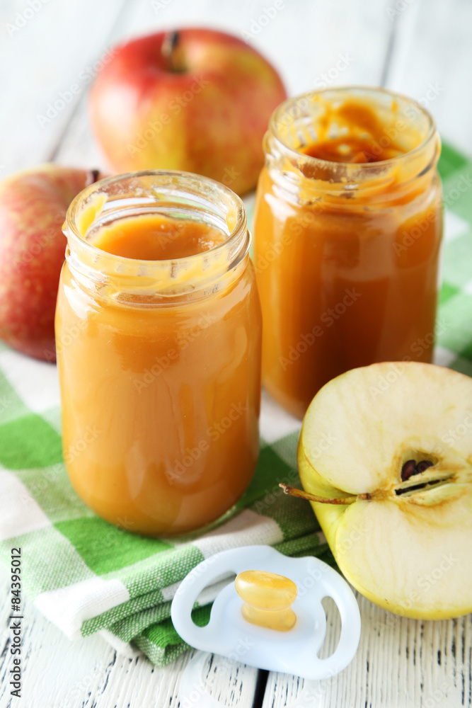 Jars of baby puree with apples on white wooden background Jars of baby puree with apples on white wooden background
