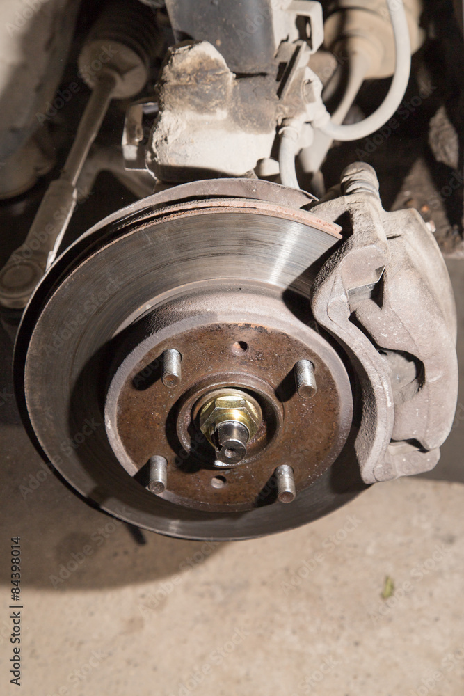 Car under repair on hoist at service station.