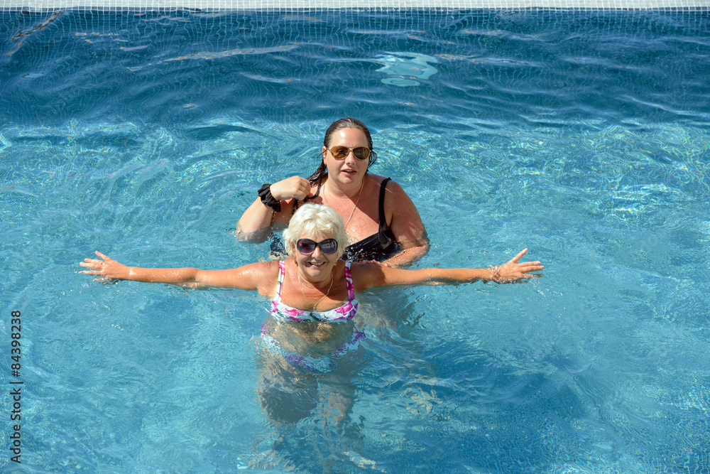 Women are doing spa exercises in water of swimming pool.