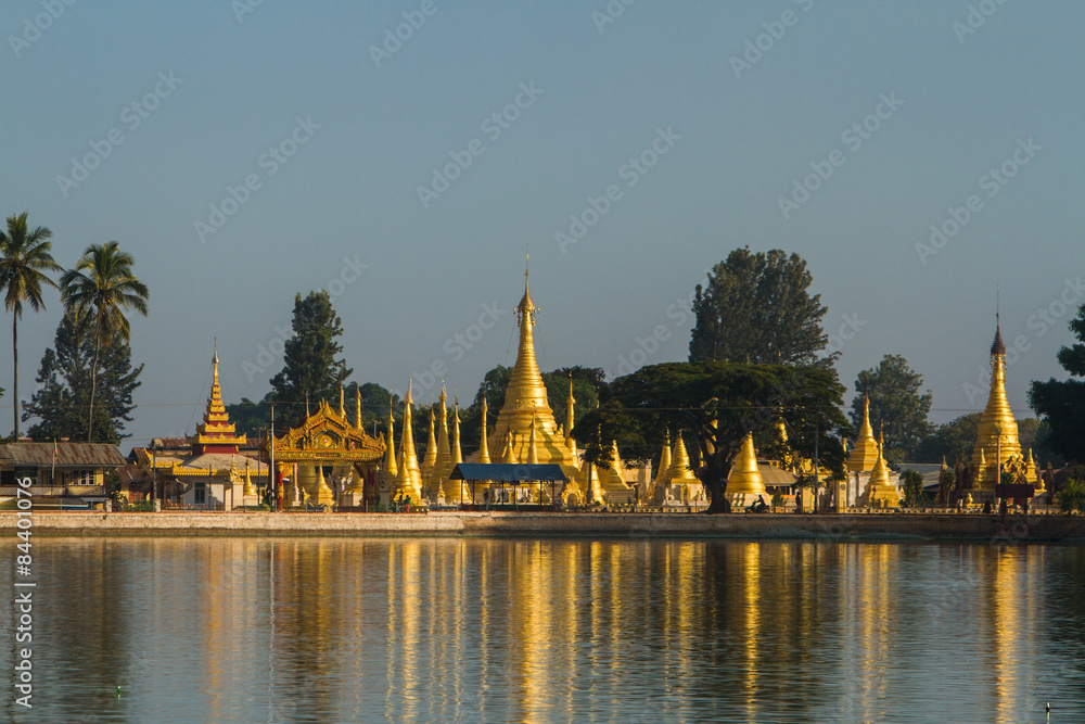 Golden stupas shimmer in Pone Taloke Lake, Pindaya, Myanmar in the morning sun.