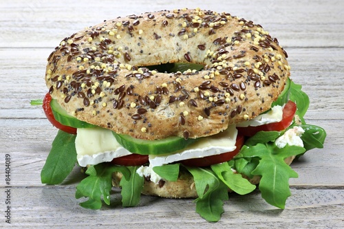 Käsebagel mit Rucola auf Holztisch photo