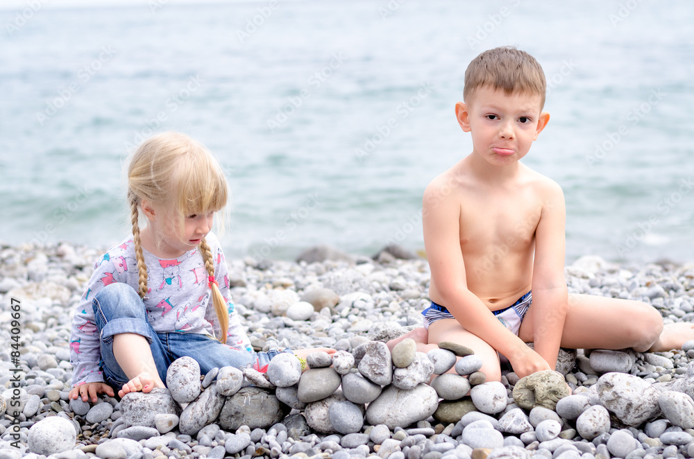 Boy and Girl Building Stone Wall on Rocky Beach Boy and Girl Building Stone Wall on Rocky Beach