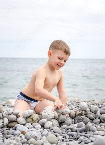 Young Boy Building Stone Wall on Rocky Beach