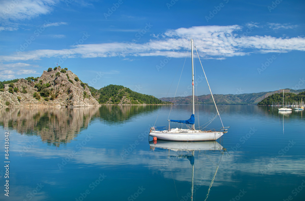 white yacht in sea near rocky island with mountains and small ma
