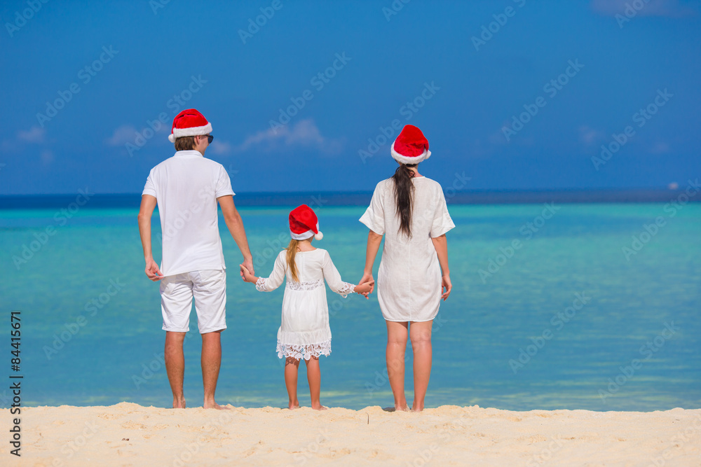 Happy family of three in Santa Hats on beach Happy family of three in Santa Hats on beach