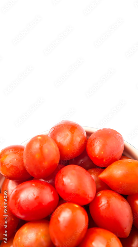 Bite sized red cherry grape tomato in blue pot over white background Bite sized red cherry grape tomato in blue pot over white background