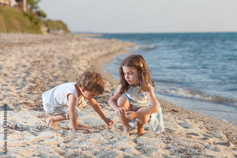 Two cute little siblings playing on the beach