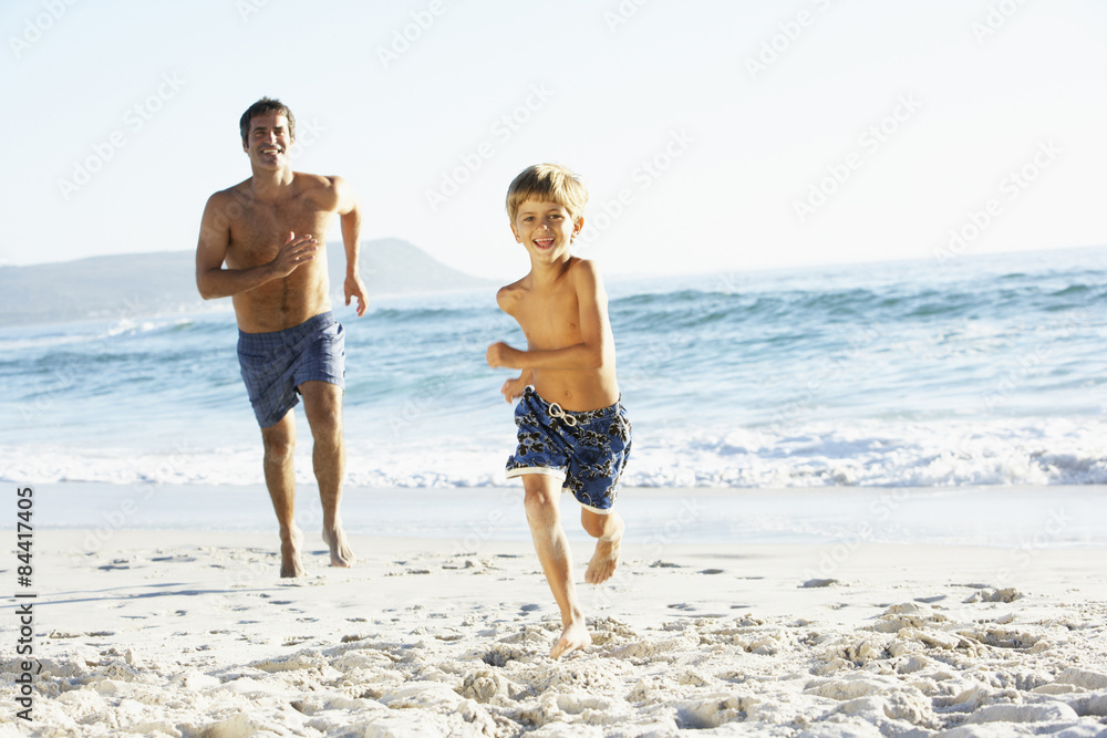 Father And Son On Holiday Running Along Beach Father And Son On Holiday Running Along Beach