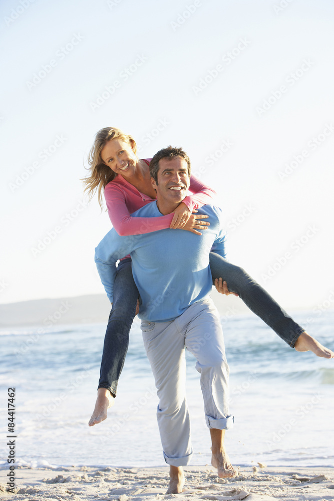Man Giving Woman Piggyback On Beach