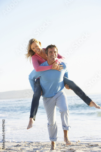Man Giving Woman Piggyback On Beach
