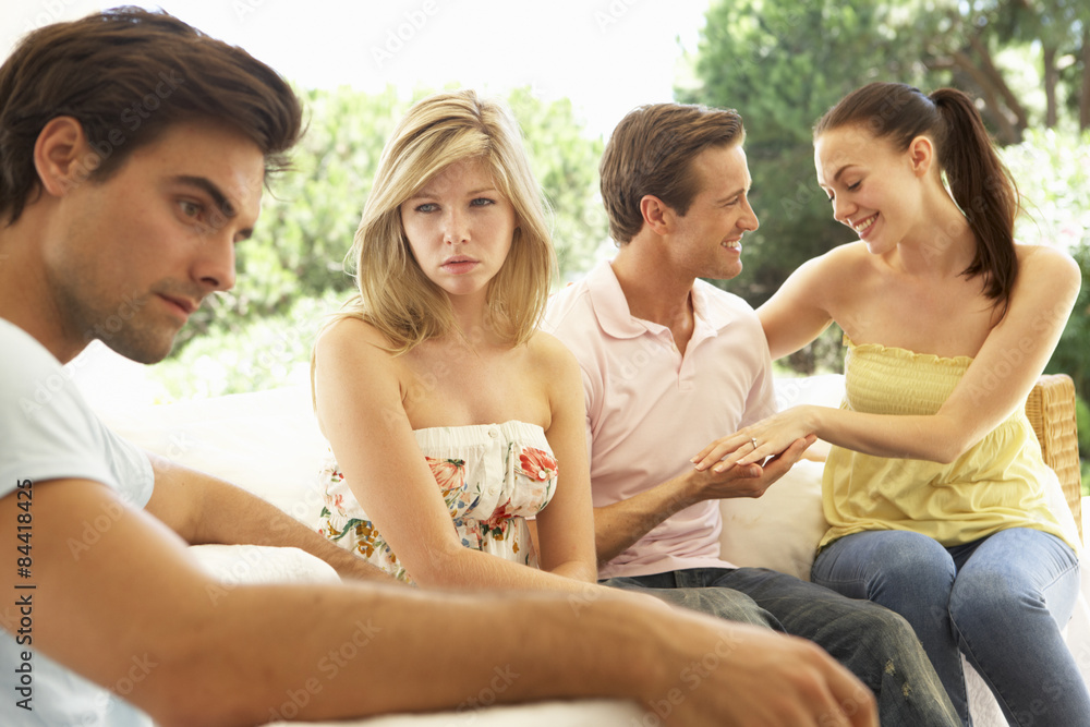 Couple With Problems Amongst Group Of Friends Relaxing On Sofa Couple With Problems Amongst Group Of Friends Relaxing On Sofa